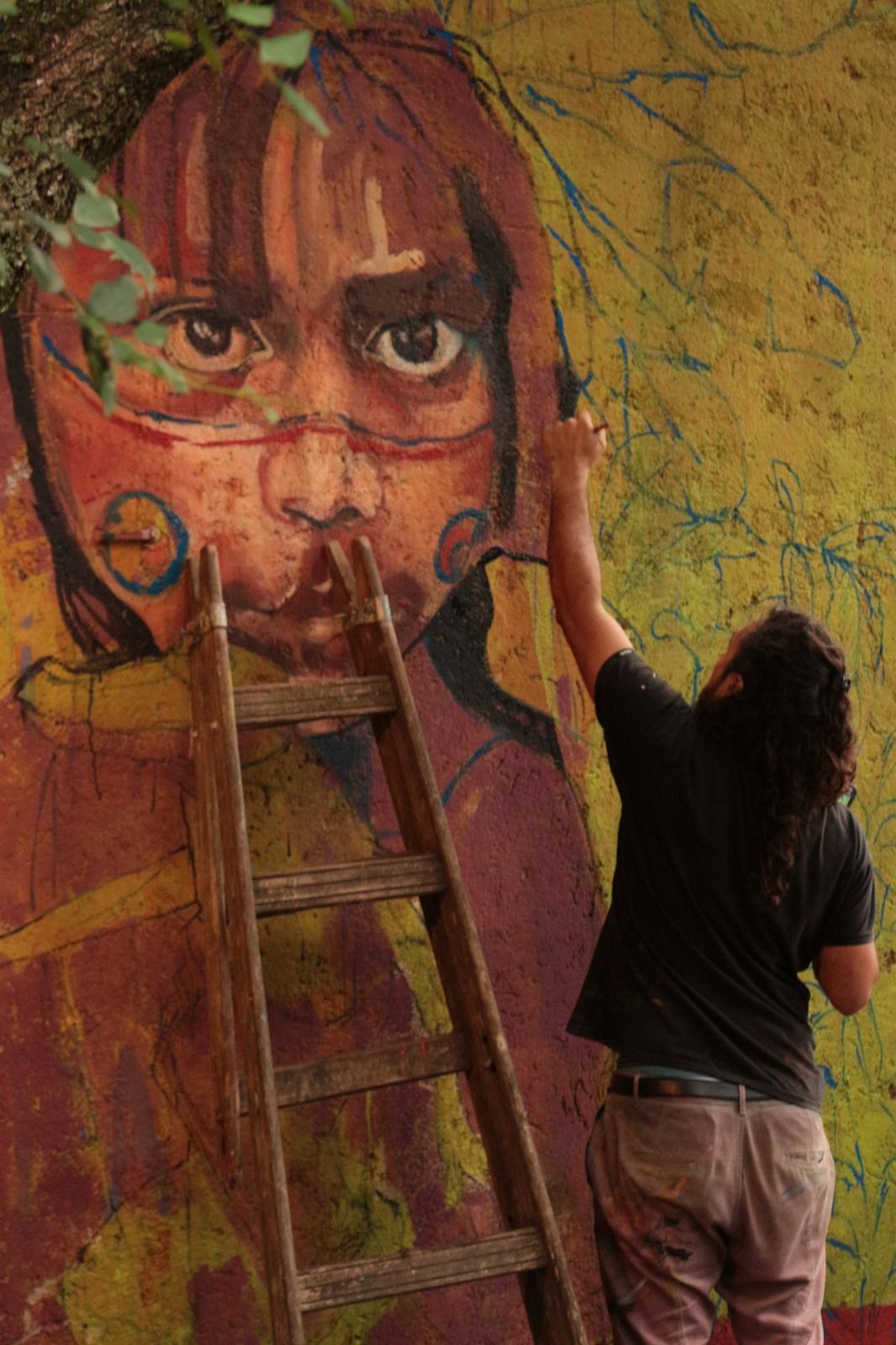 Artist painting a mural at La Lomita hostel in Salsipuedes