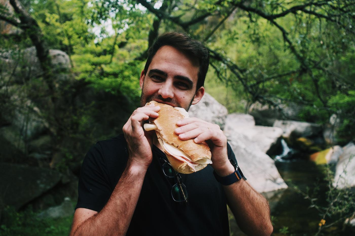 Guest eating a sandwich by the river
